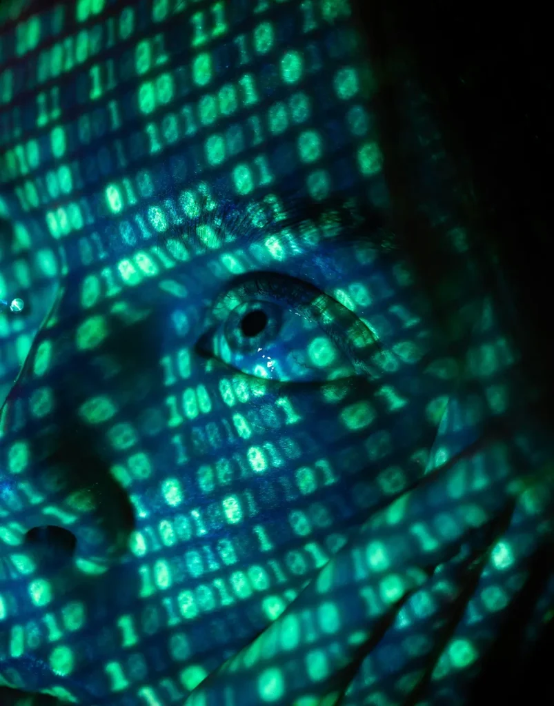 Persona con un reflejo de pantalla con números binarios de color negro y verde, como si fuera Matrix